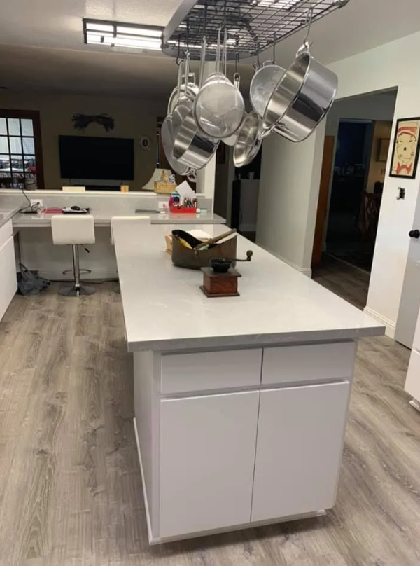 Modern white kitchen island with quartz countertop and hanging pot rack in Madera, CA