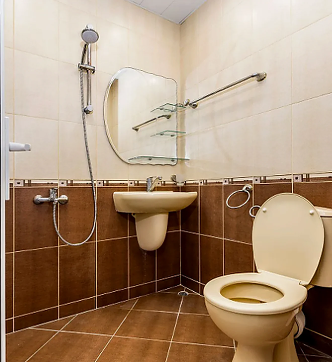 Dated bathroom before remodel with beige fixtures and brown tile