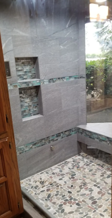 Gray stone-look tile shower with glass mosaic accent bands and pebble floor in Fresno, CA