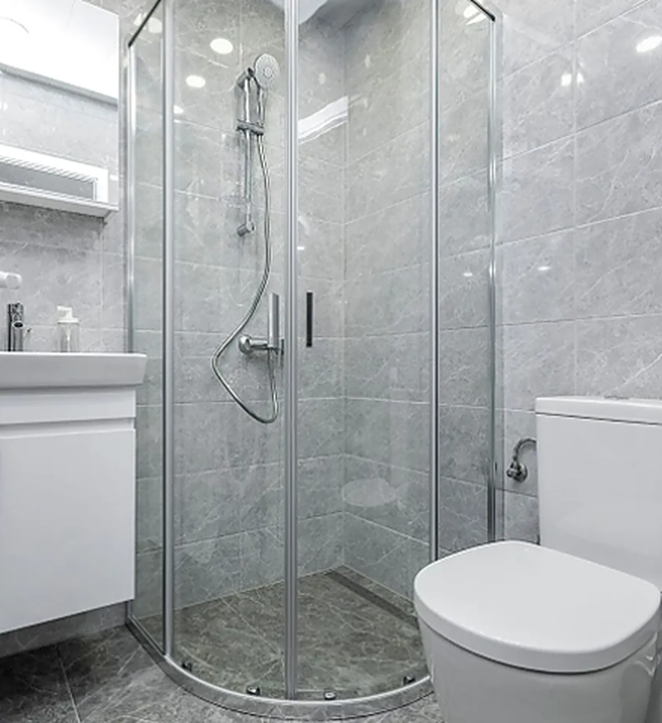 Remodeled bathroom with gray tile, glass corner shower and white floating vanity